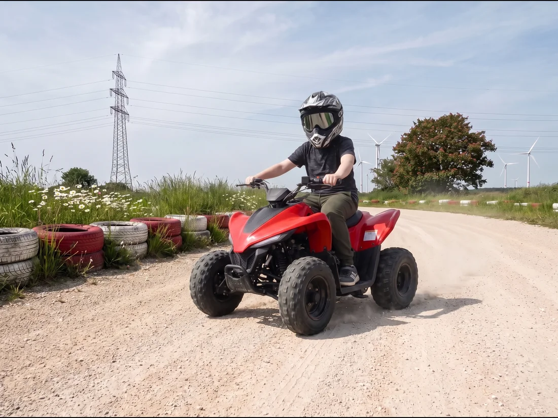 Kind mit Helm und Brille fährt auf einem roten Kinderquad über die Schotterstrecke