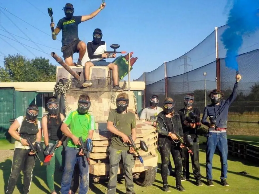 Gruppe mit Markierern und blauer Rauchgranate vor einem Panzer-Nachbau
